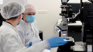 two photonics engineers working in a clean room wearing protective equipment