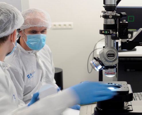 two photonics engineers working in a clean room wearing protective equipment