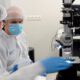 two photonics engineers working in a clean room wearing protective equipment