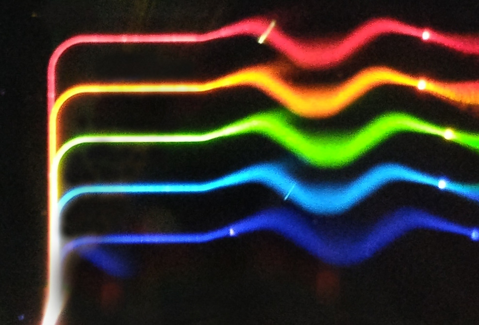 A silicon nitride chip splitting white light into many component channels, manufactured by LioniX International.