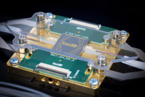 A photograph of a dummy multi-project wafer chip in our characterisation package, with fiber arrays, electronic interconnects, stress reliefs, and a copper block for thermal management.