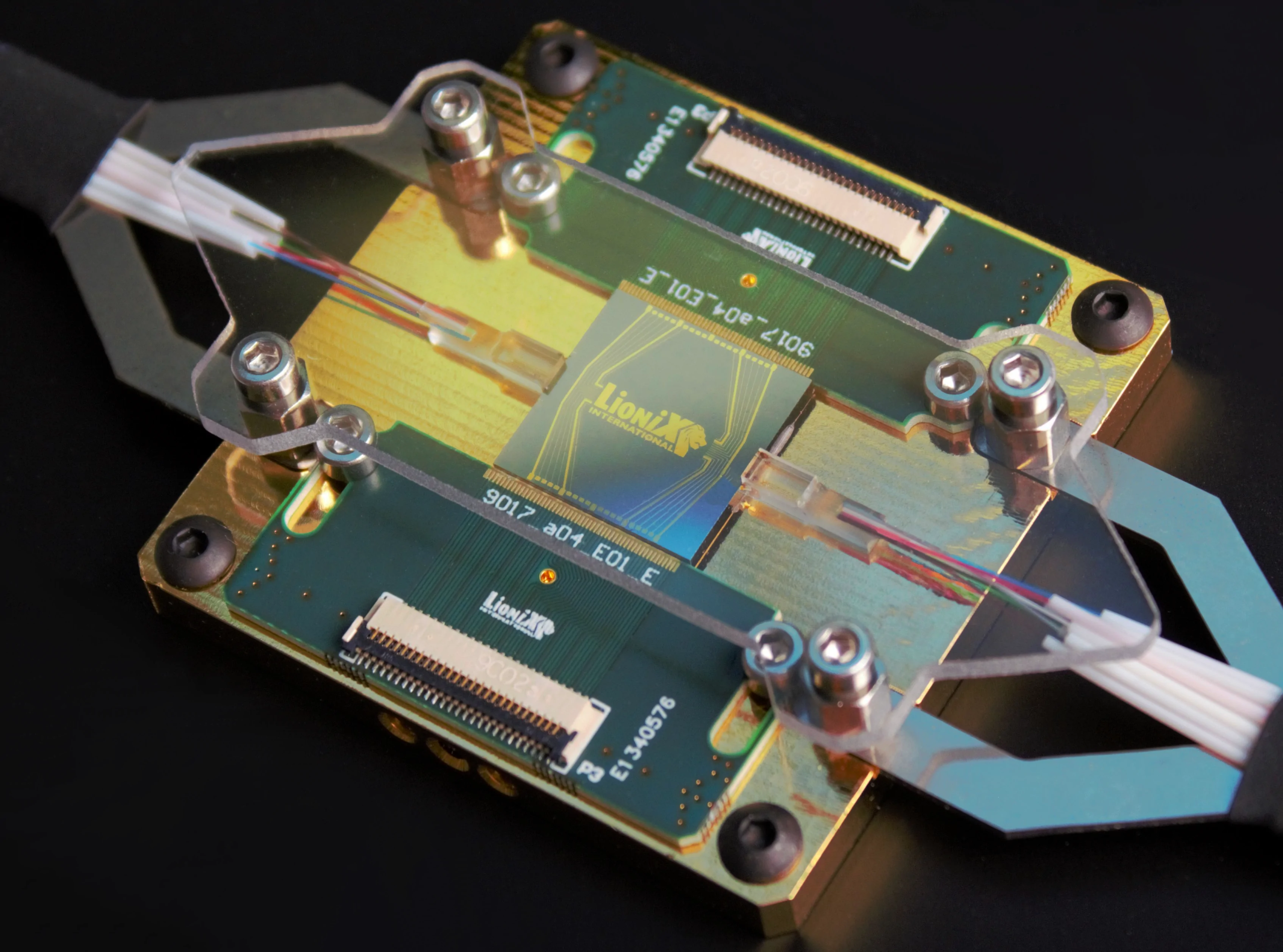 A photograph of a dummy multi-project wafer chip in our characterization package which includes fiber arrays, electronic interconnects, stress reliefs, and a copper block for thermal management.