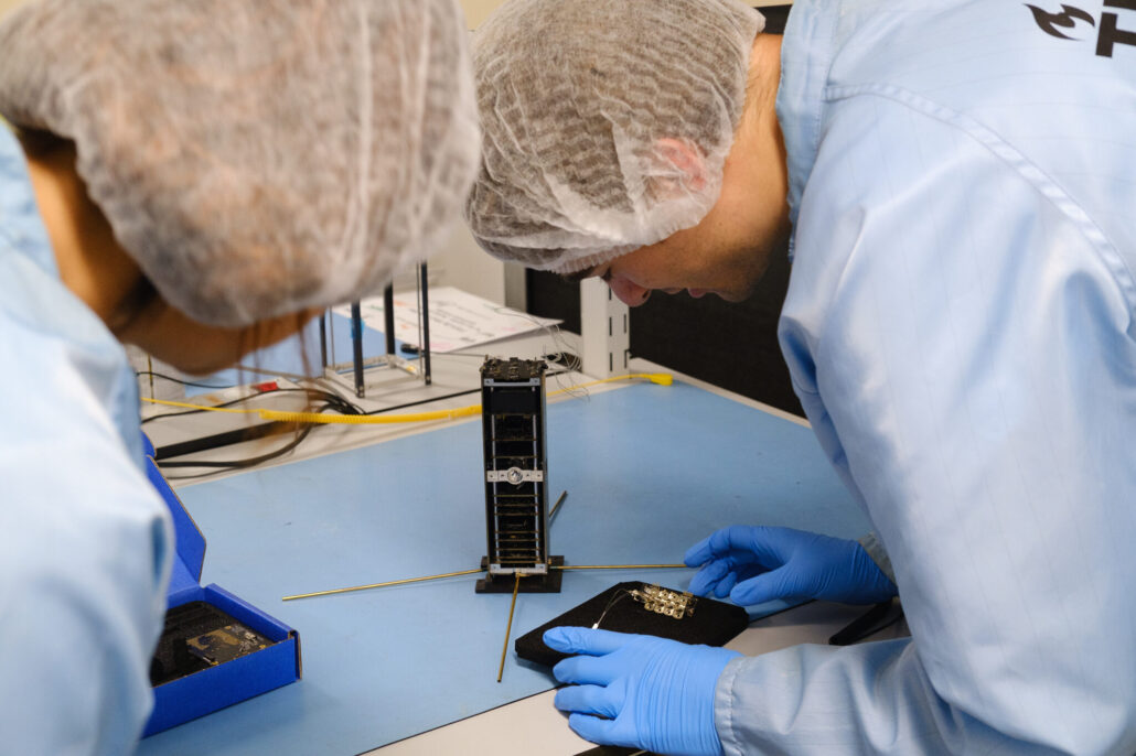 The PRISM payload with the asymmetric Mach-Zehnder Interferometer photonic chip, laser and photodiode, together with the PocketQube satellite bus it will fly on 6 TU Delft team members Vidhya Pallichadath and Bavo Vlyminckx working with the components.